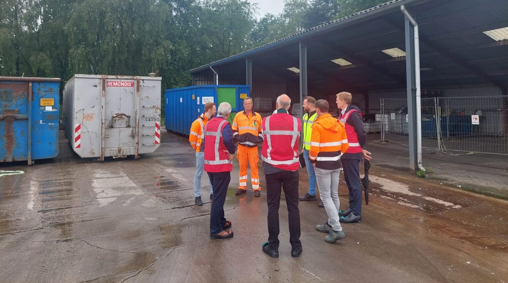 Personen die in een groepje bij afvalcontainers staan.